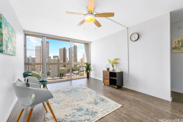 living area featuring ceiling fan, dark hardwood / wood-style flooring, and a wall of windows