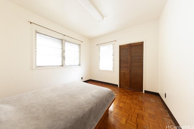 unfurnished bedroom featuring dark parquet flooring and a closet