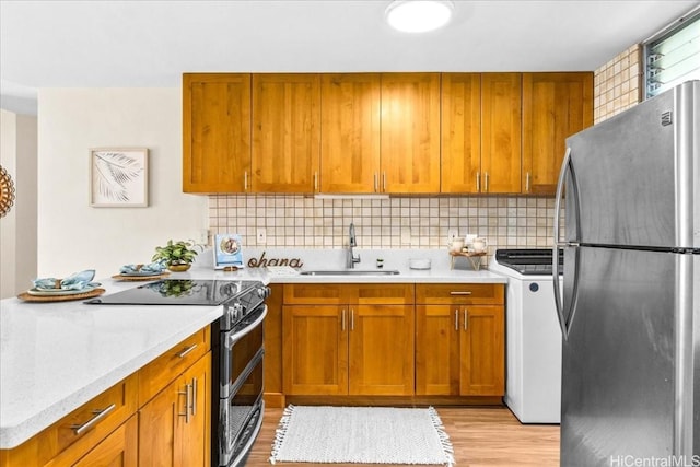 kitchen featuring decorative backsplash, washer / clothes dryer, stainless steel appliances, and a sink