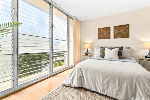 bedroom featuring concrete block wall and wood finished floors