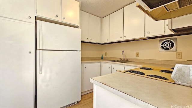 kitchen featuring a textured ceiling, sink, white fridge, and white cabinets