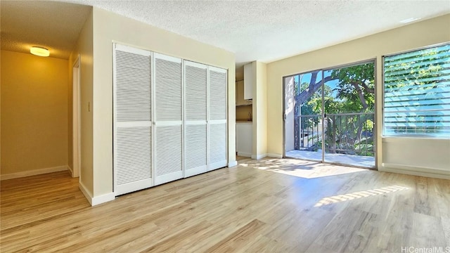 unfurnished bedroom featuring light hardwood / wood-style flooring, access to outside, a closet, and a textured ceiling