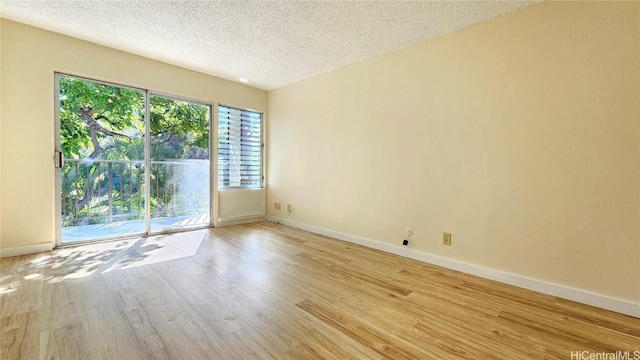 spare room with baseboards, a textured ceiling, and light wood finished floors