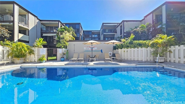 community pool with a patio area and fence