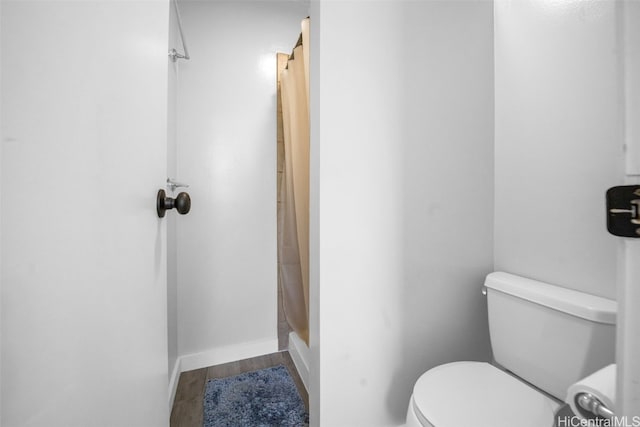 bathroom with a shower with curtain, wood-type flooring, and toilet