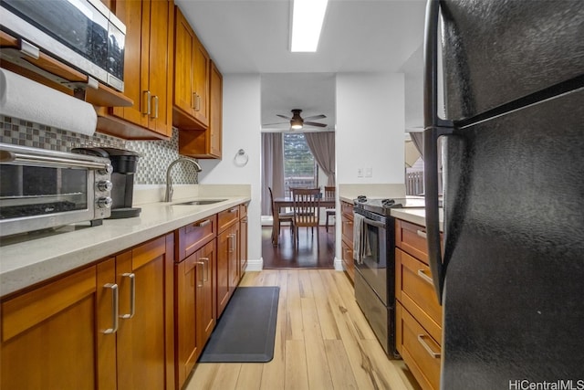 kitchen featuring sink, electric range oven, light hardwood / wood-style flooring, black refrigerator, and backsplash