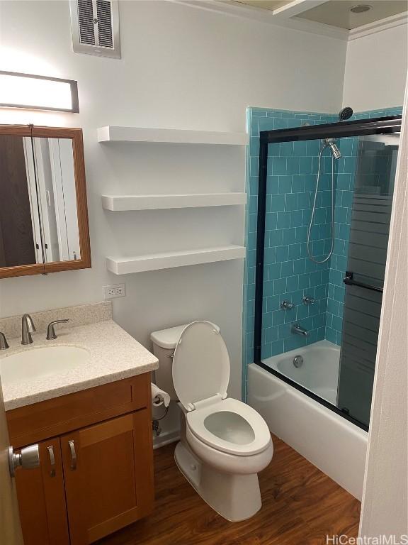 full bathroom with bath / shower combo with glass door, vanity, wood-type flooring, and toilet