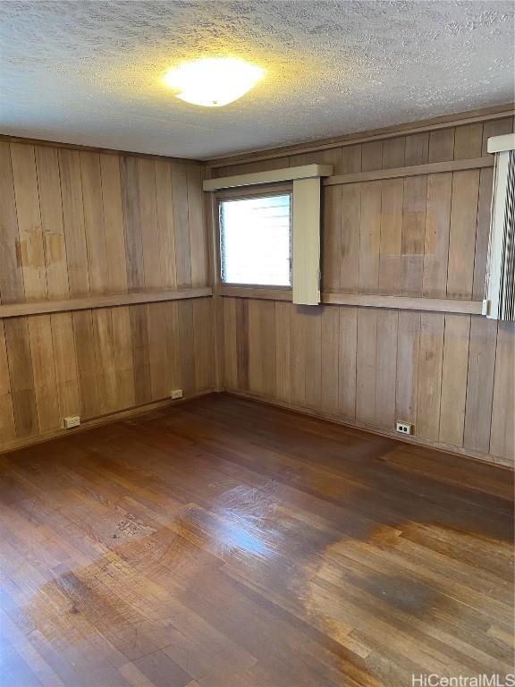 empty room with dark wood-type flooring and a textured ceiling