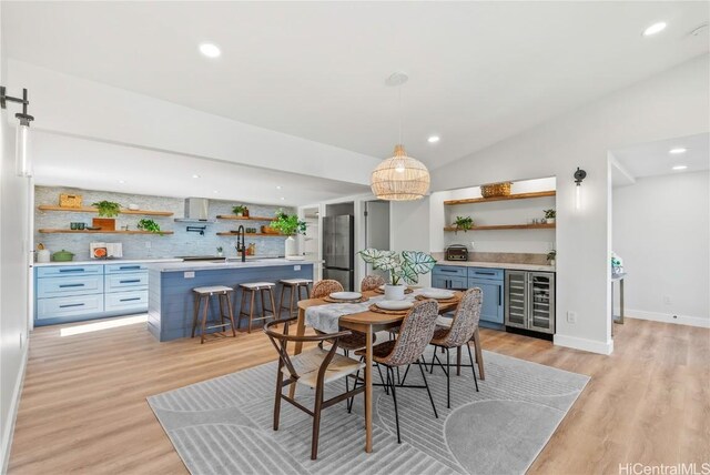 dining area featuring baseboards, lofted ceiling, wine cooler, light wood-style floors, and recessed lighting