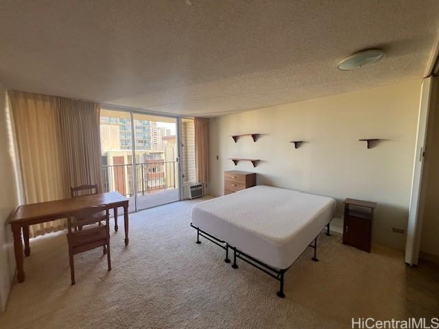 carpeted bedroom with a wall of windows, access to exterior, and a textured ceiling