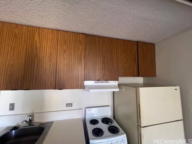 kitchen featuring sink, a textured ceiling, and white appliances