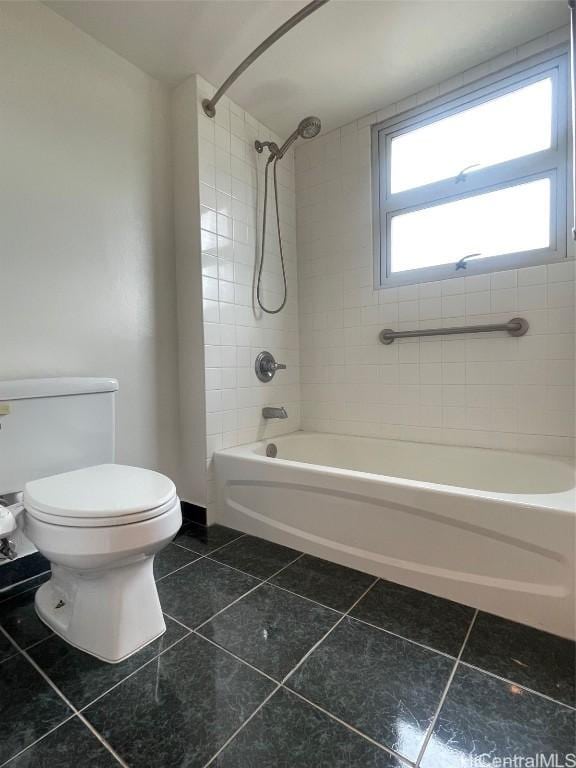 bathroom featuring tiled shower / bath combo, tile patterned flooring, and toilet