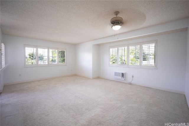 spare room with ceiling fan, carpet, an AC wall unit, and a textured ceiling