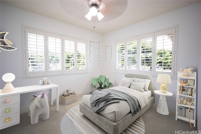 carpeted bedroom featuring multiple windows, ceiling fan, and a textured ceiling