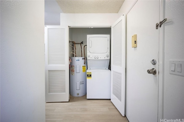 washroom with stacked washer and dryer, light hardwood / wood-style floors, water heater, and a textured ceiling