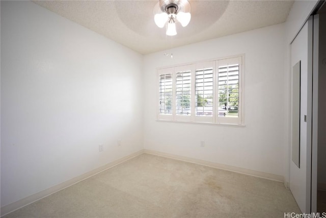 carpeted empty room featuring ceiling fan and a textured ceiling