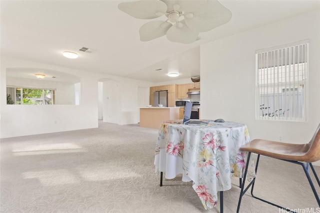 interior space with arched walkways, a ceiling fan, visible vents, and light colored carpet