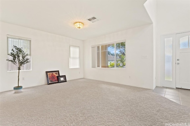 interior space with light carpet, visible vents, and a healthy amount of sunlight
