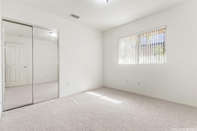 unfurnished bedroom with carpet, visible vents, and a closet