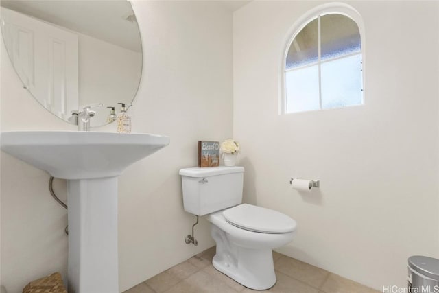 half bathroom with toilet and tile patterned flooring