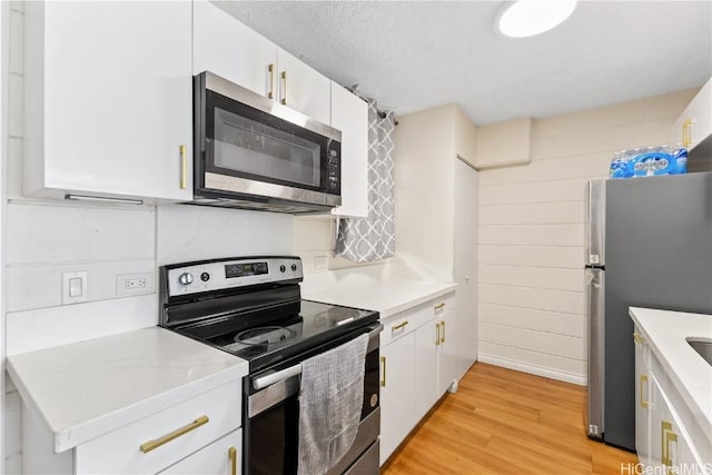 kitchen featuring light wood-style floors, white cabinetry, stainless steel appliances, and a textured ceiling