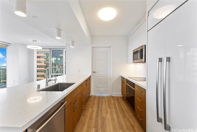 kitchen with sink, appliances with stainless steel finishes, white cabinetry, kitchen peninsula, and light wood-type flooring