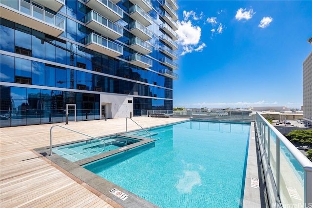 pool with fence and a hot tub