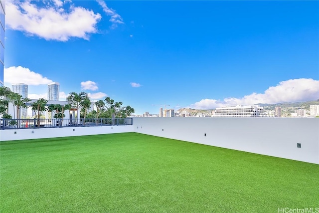 surrounding community with a view of city, a yard, and fence