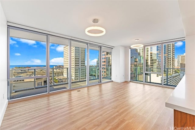 empty room with light wood-style flooring, floor to ceiling windows, and a city view