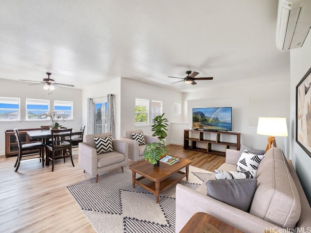 living room featuring ceiling fan, light hardwood / wood-style floors, and a wall unit AC