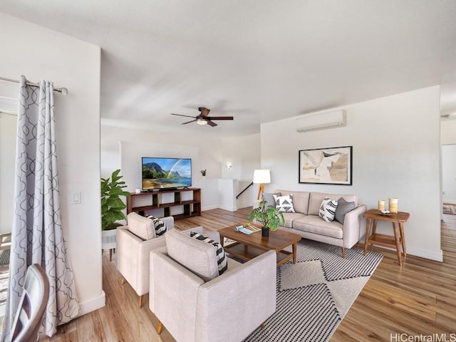 living room with a wall mounted air conditioner, ceiling fan, and light wood-type flooring