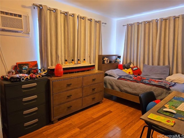 bedroom with light hardwood / wood-style floors and a wall unit AC