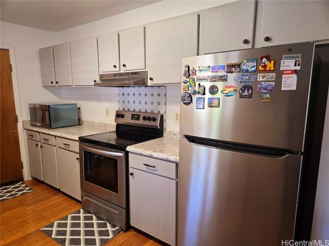 kitchen with light stone counters, stainless steel appliances, and light wood-type flooring