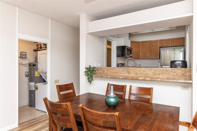 1020 Aoloa Pl Unit 109B, Kailua, HI 96734 - dining room with water heater, light wood-style floors, a textured ceiling, and baseboards