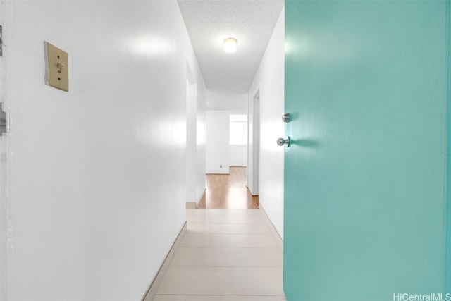 hallway featuring a textured ceiling and baseboards