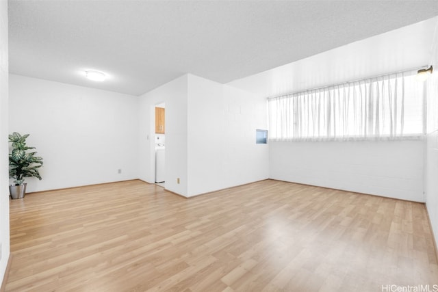 empty room with light wood-style floors and a textured ceiling