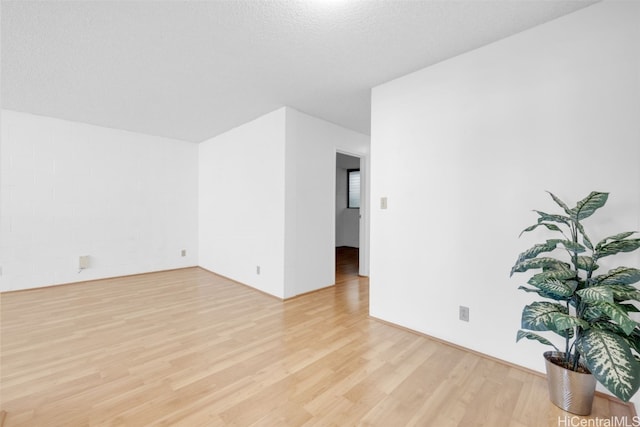 empty room with light wood-style flooring and a textured ceiling