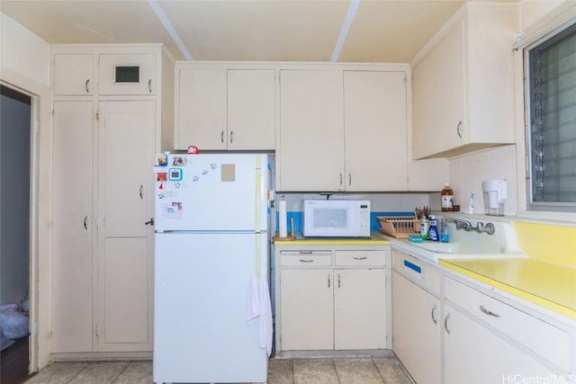 kitchen with white appliances, white cabinetry, and light countertops