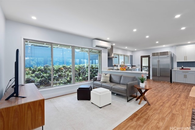 living room with a wall mounted air conditioner and light wood-type flooring