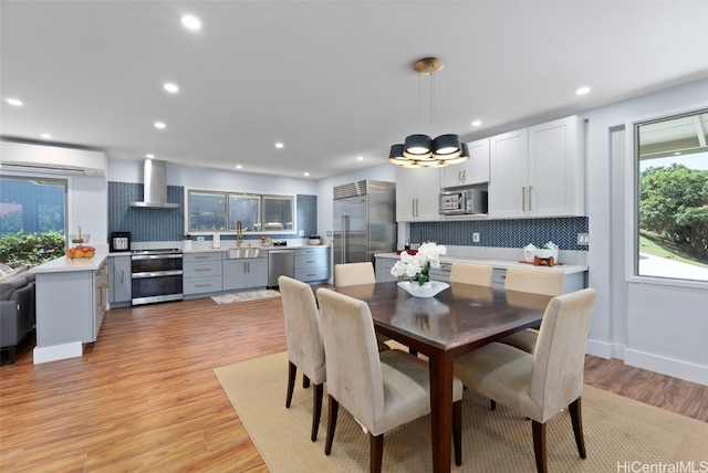 dining space with sink, light hardwood / wood-style floors, and a wall mounted AC