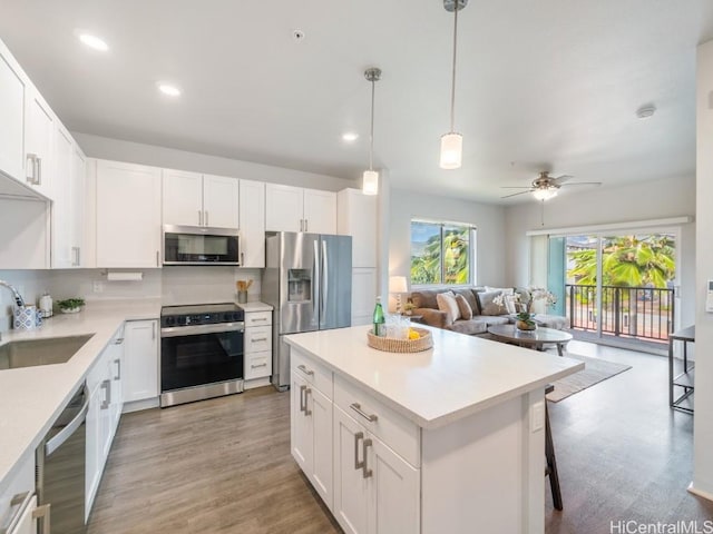 kitchen with white cabinetry, stainless steel appliances, sink, and hanging light fixtures