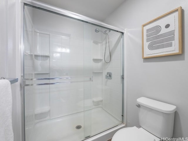 bathroom featuring toilet and a shower with shower door