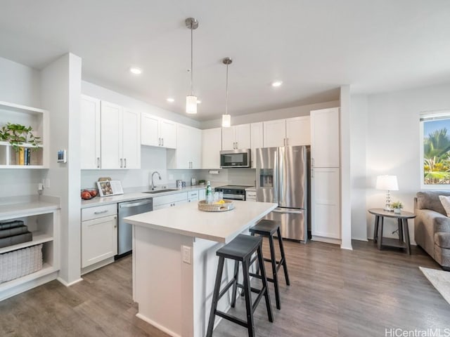 kitchen featuring sink, a breakfast bar, appliances with stainless steel finishes, white cabinets, and decorative light fixtures