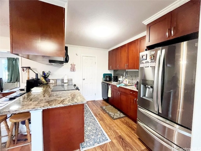 kitchen with a breakfast bar, crown molding, light wood-type flooring, stainless steel fridge, and light stone countertops