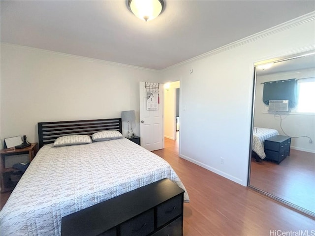 bedroom with crown molding, cooling unit, hardwood / wood-style flooring, and a closet