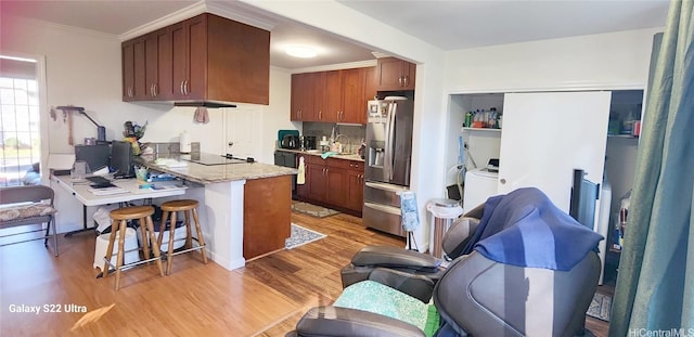 kitchen with a kitchen bar, sink, light hardwood / wood-style flooring, ornamental molding, and black appliances