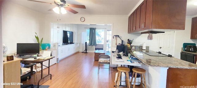 kitchen with a breakfast bar, crown molding, light hardwood / wood-style flooring, ceiling fan, and black appliances