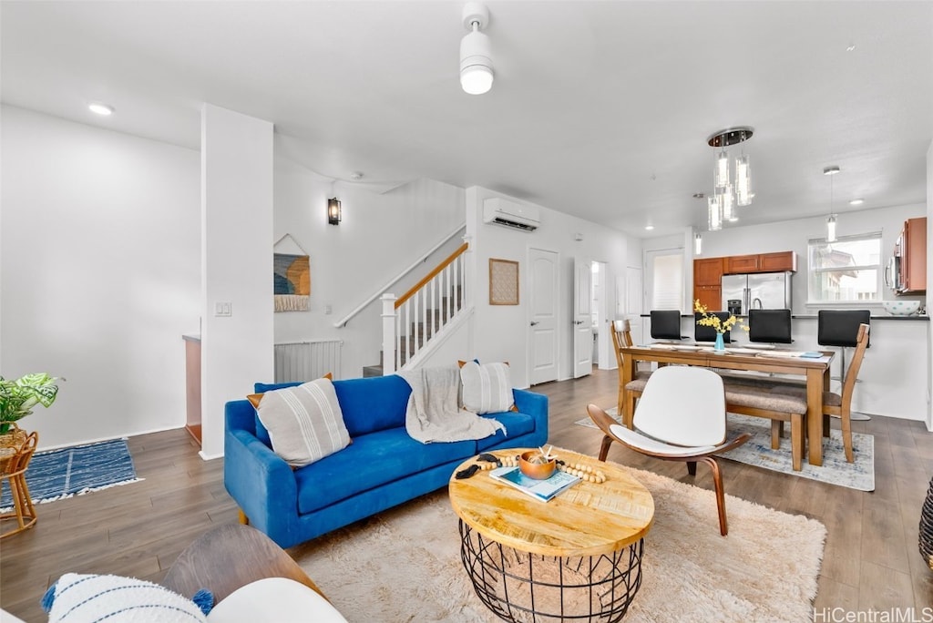 living room featuring a wall mounted air conditioner and light hardwood / wood-style flooring