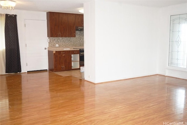 interior space featuring tasteful backsplash, range, a chandelier, and light hardwood / wood-style flooring