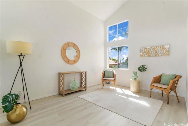 sitting room with high vaulted ceiling and light hardwood / wood-style floors